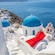 A woman wearing a long flowing dress near a seaside domed church in Santorini, Greece